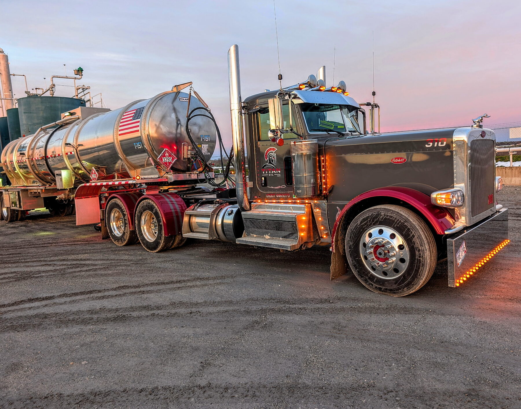 Titan Oil truck 310 lit up at dusk with a crude tanker