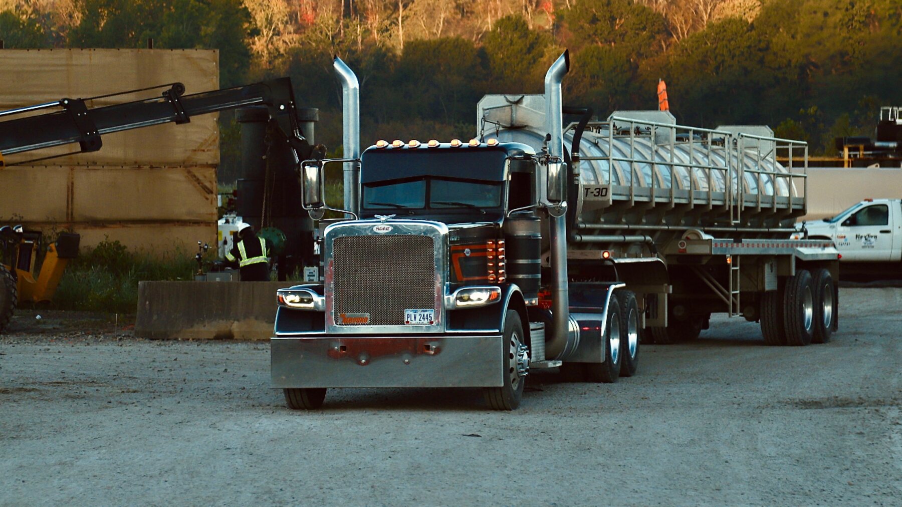 Titan water truck with vacuum tanker at dusk on a well pad